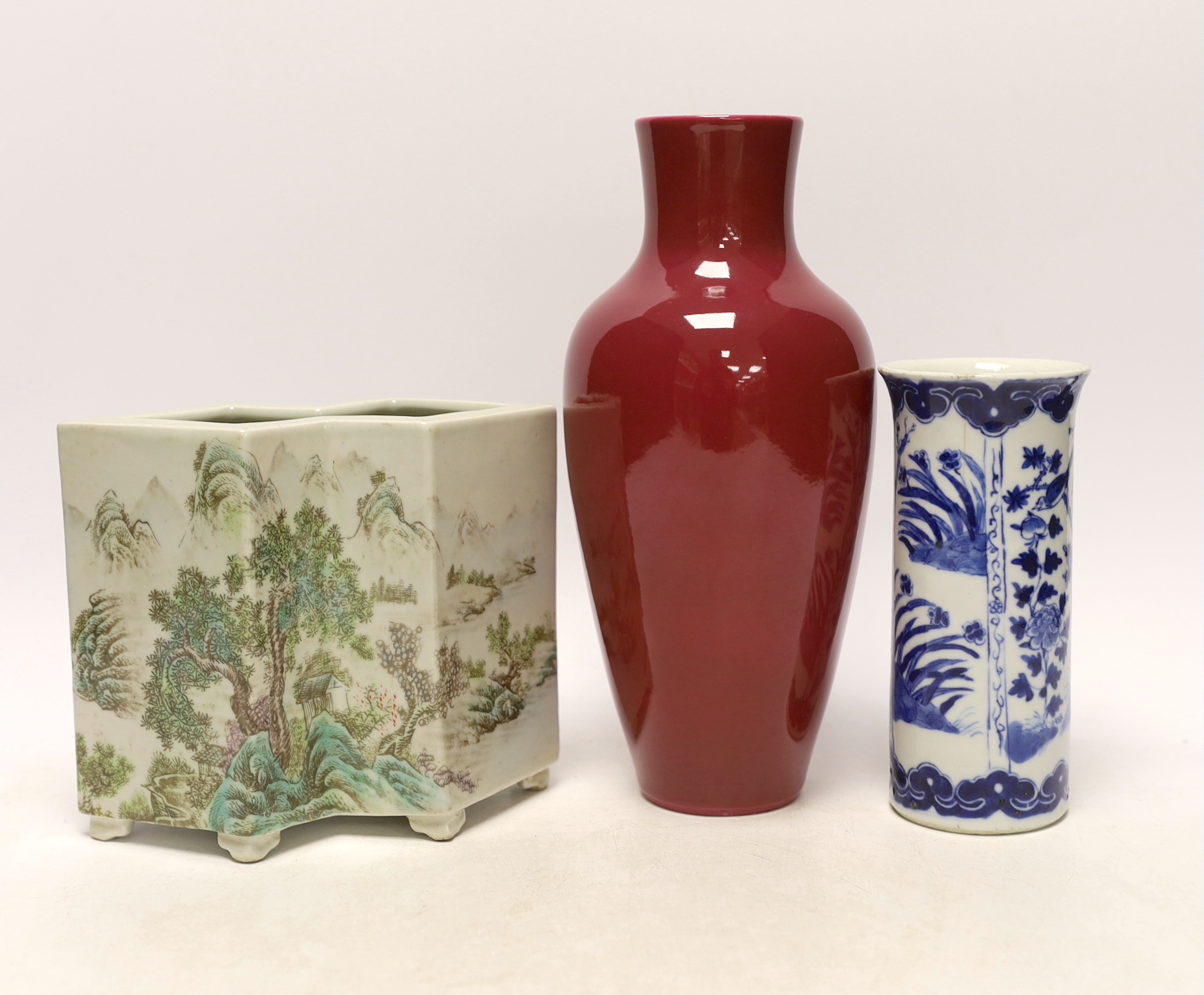 An early 20th century Chinese blue and white cylindrical vase, a ruby ground vase and an enamelled porcelain double lozenge vase, largest 24cm high (3)
